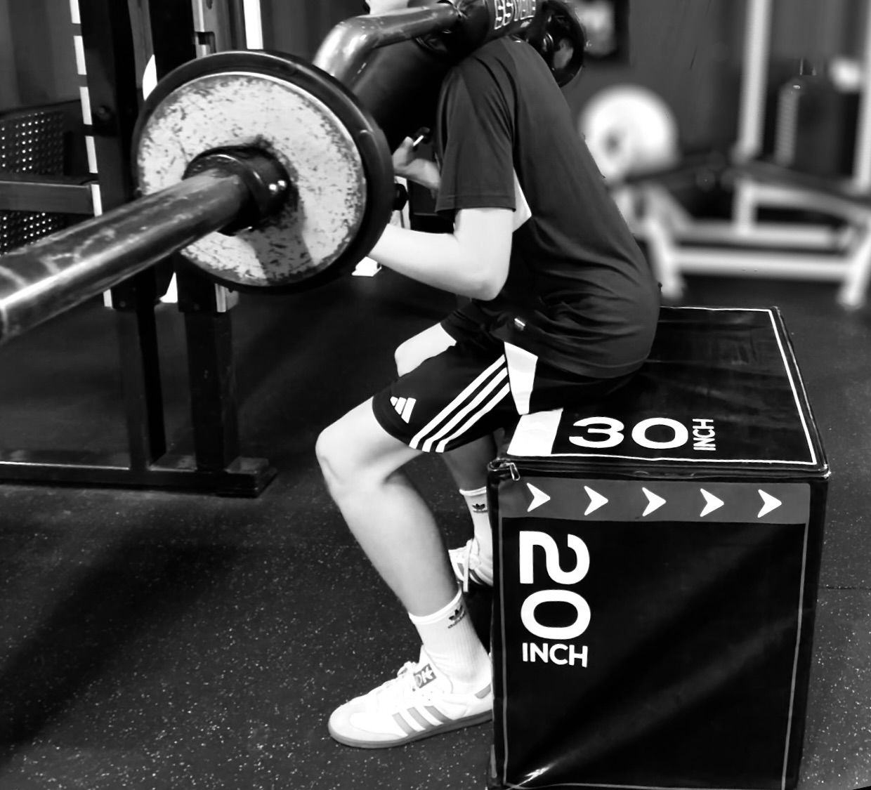 Athlete performing a box squat at Bax Performance and Rehab in Pleasanton, CA to reduce knee pain and improve strength through proper squat mechanics.