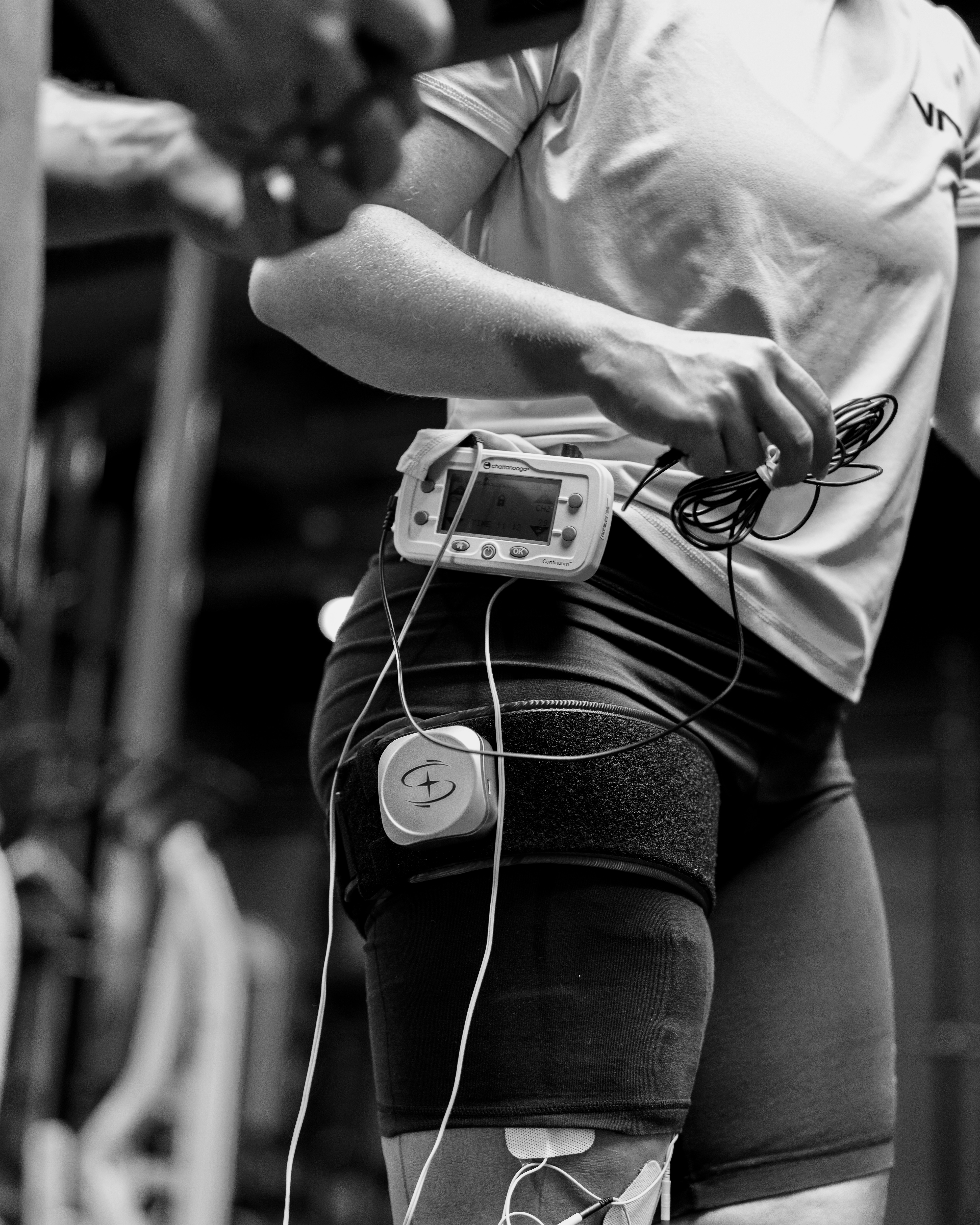 Athlete in Pleasanton using blood flow restriction (BFR) and neuromuscular electrical stimulation (NMES) during physical therapy for recovery and strength training.
